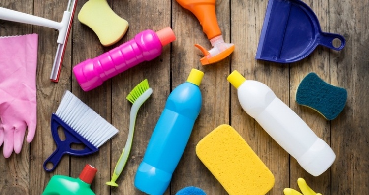 Variety of cleaning tools and bootles laying on a hardwood floor