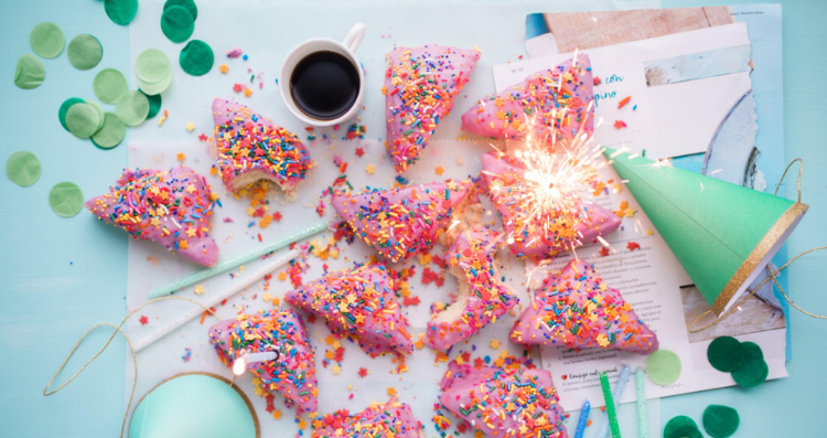 A table at a party covered in party hats, cake, and confetti