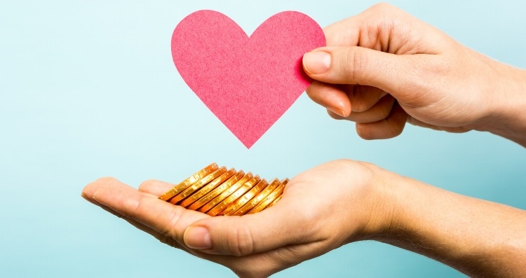 Two hands holding a red heart and money as a symbol of Facebook Donate